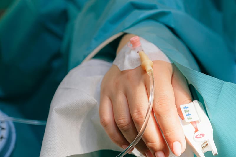 Mão de paciente com acesso intravenoso e monitoramento, representando atendimento em UTI Aérea.
